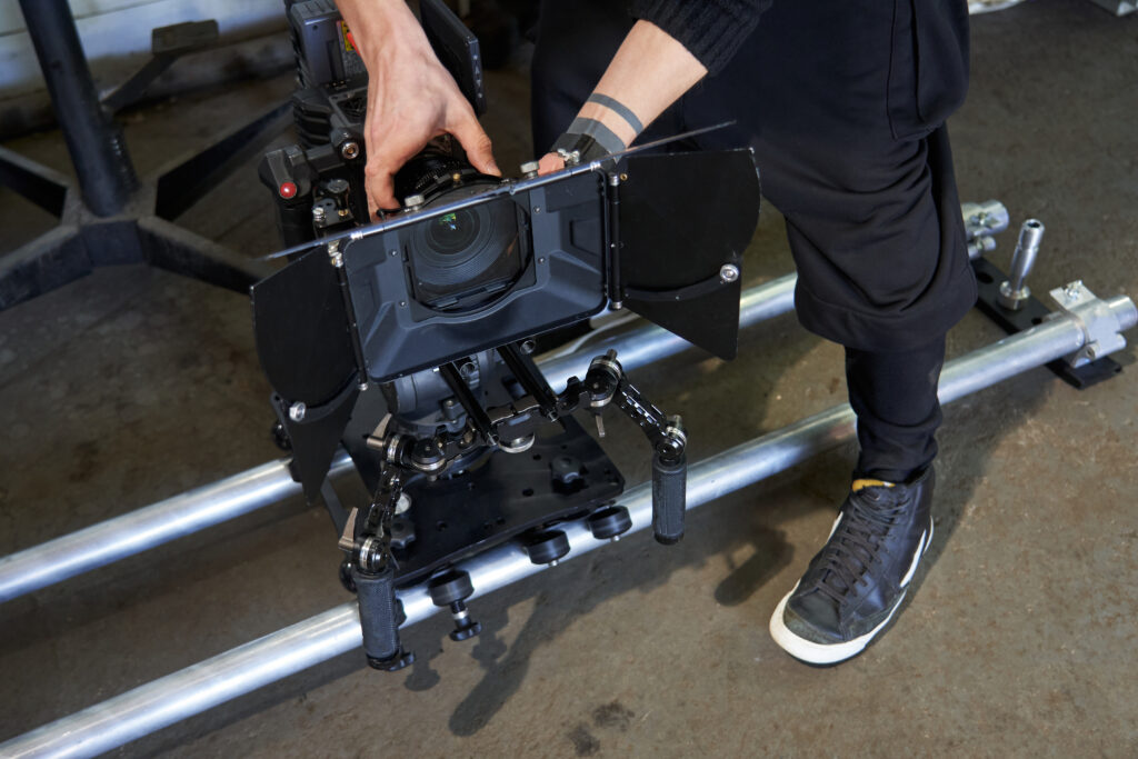 male hands of a videographer set up a professional movie camera. the video camera stands on a camera trolley and rails on the floor. High quality photo